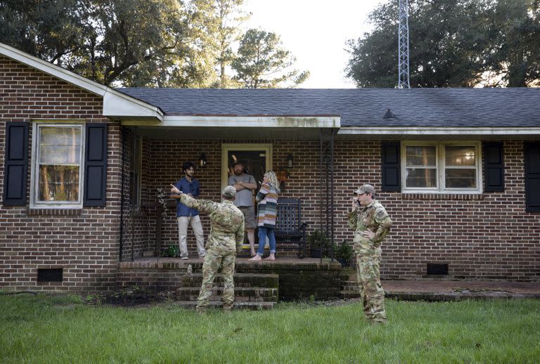 Miembros de la Base Conjunta Charleston hablan con una familia que vive justo al lado del lugar donde se estrelló un F-35 en el condado de Williamsburg, Carolina del Sur, el lunes 18 de septiembre de 2023.