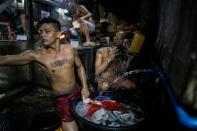 An inmate (C-top) cooks his dinner as other detainees take a bath inside the Quezon City Jail in Manila