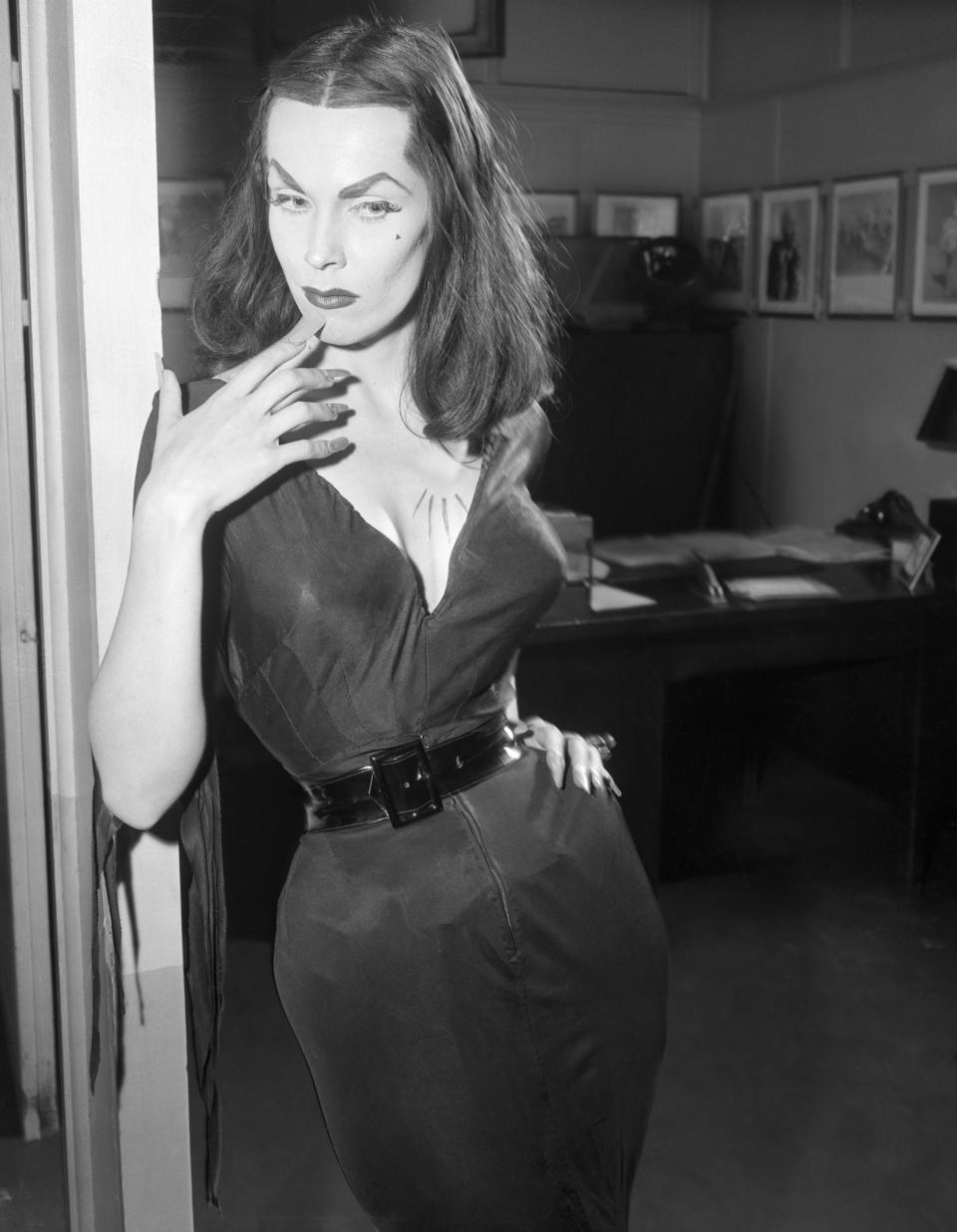 Vampira, the campy 1950s TV personality played by Maila Nurmi, has been dubbed the "<a href="https://www.amazon.com/exec/obidos/ASIN/1593765436/boingboing" target="_blank" rel="noopener noreferrer">dark goddess of horror</a>." Her look was one part Bettie Page, one part Morticia Addams and one part gothic '50s housewife. To recreate her style, you'll need a fitted black dress, some red lipstick, some extra-long red nails and severely arched brows. To finish everything off, wrap a chunky belt around your waist.