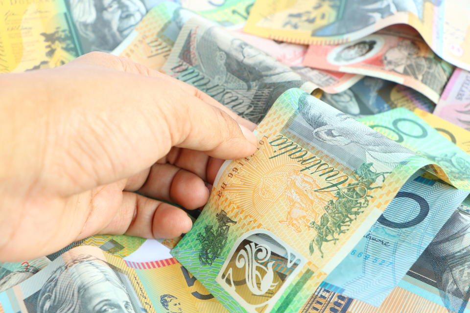 Asian woman hand taking green 100 australian banknote from group of colorful australian money banknote dollar (AUD) pile background