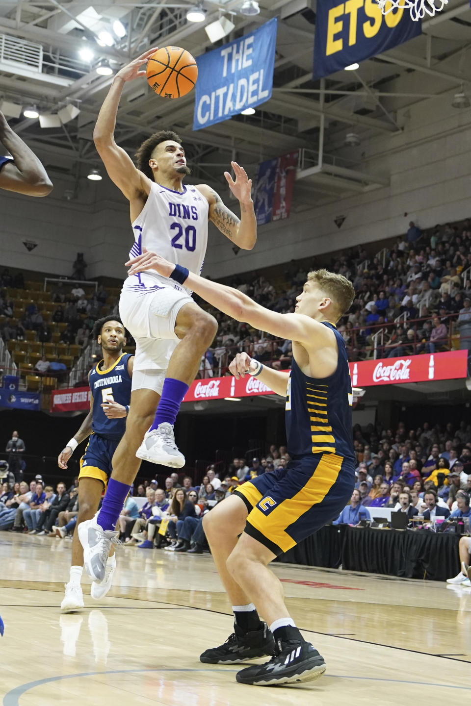 Furman forward Jalen Slawson (20) leaps to the basket over Chattanooga center Jake Stephens, right, during the second half of an NCAA men's college basketball championship game for the Southern Conference tournament, Monday, March 6, 2023, in Asheville, N.C. (AP Photo/Kathy Kmonicek)