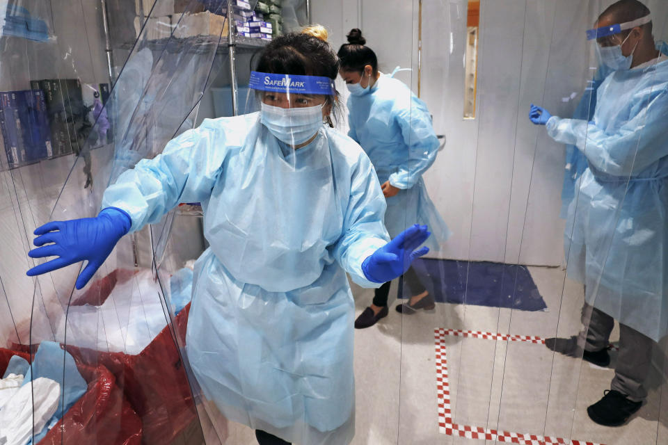 Lena Landaverde, assistant director of the Precision Diagnostics Center, heads to the new COVID-19, on-campus testing labs after donning personal protective equipment, Thursday, July 23, 2020, at Boston University in Boston. Dozens of U.S. colleges are announcing plans to test students for the coronavirus this fall, but their strategies vary widely. Federal health officials discourage widespread testing on college campuses, but some researchers say it's necessary to prevent outbreaks. (AP Photo/Charles Krupa)