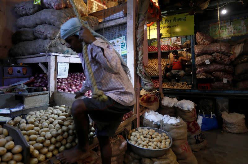 A vendor climbs to his stall as another waits for customers at a wholesale vegetable market in Mumbai