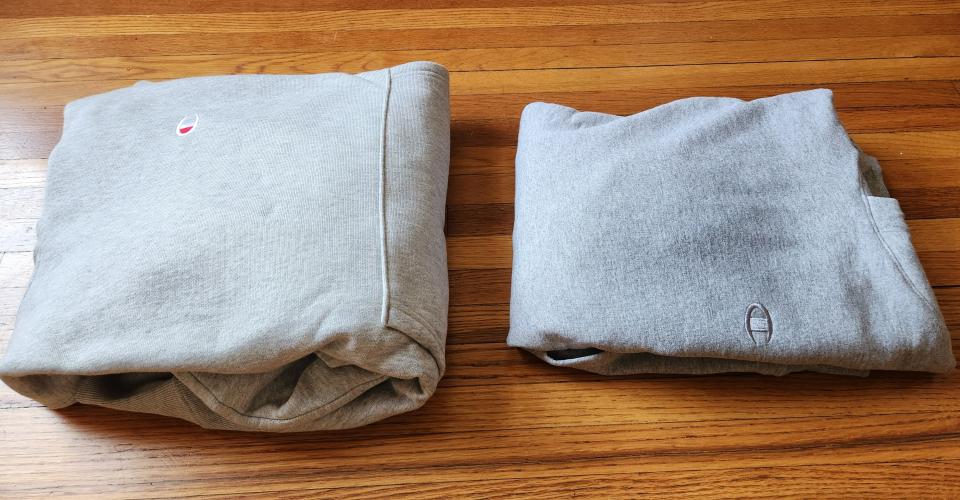 two champion hoodies folded side by side on a wood floor