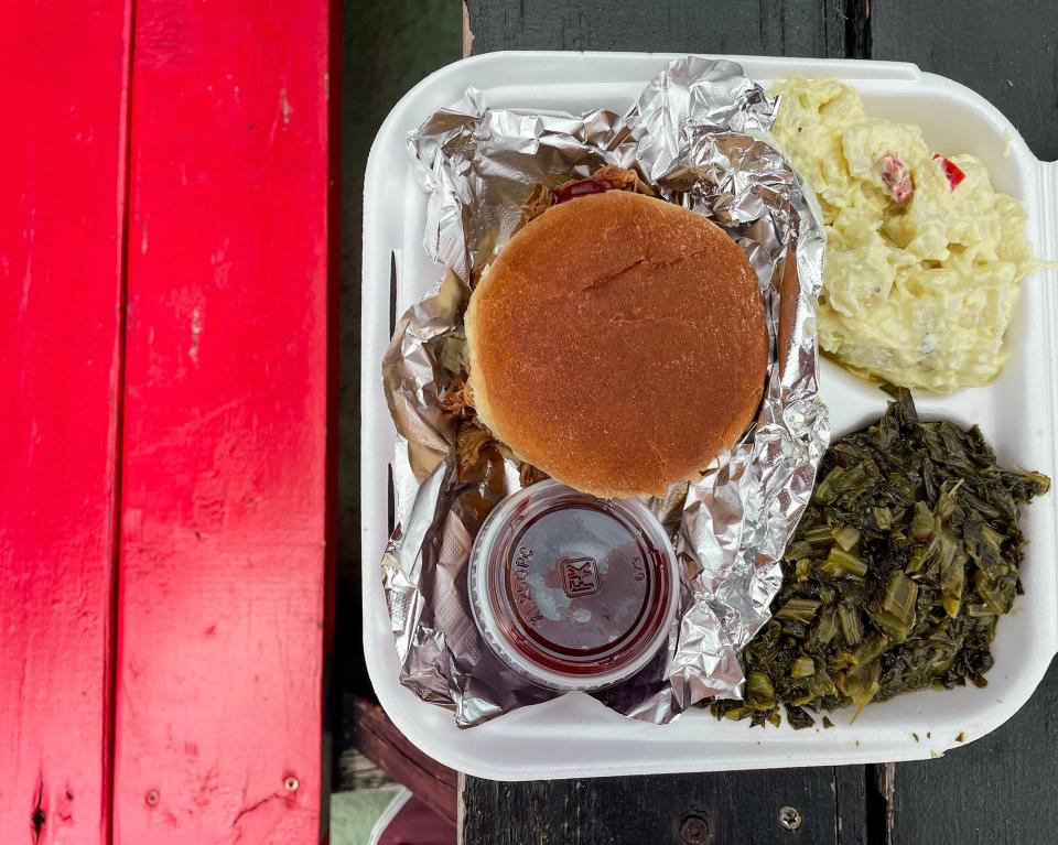 This photo taken at Dawg Gone Good BBQ in Athens, Ga. on Jul. 12, 2022 shows a pulled pork sandwich with potato salad and collard greens.