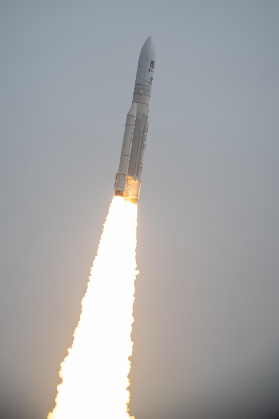 a rocket flies through the air with a massive plume of fire behind it