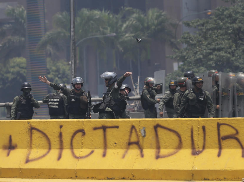 A Venezuelan Bolivarian National Guard officer throws a tear gas grenade towards demonstrators during a protest in Caracas, Venezuela, Monday, April 10, 2017. Thousands of people in Venezuela's capital are protesting against the government of President Nicolas Maduro, demanding new elections and vowing to stay in the streets during the usually quiet Easter Week.(AP Photo/Fernando Llano)