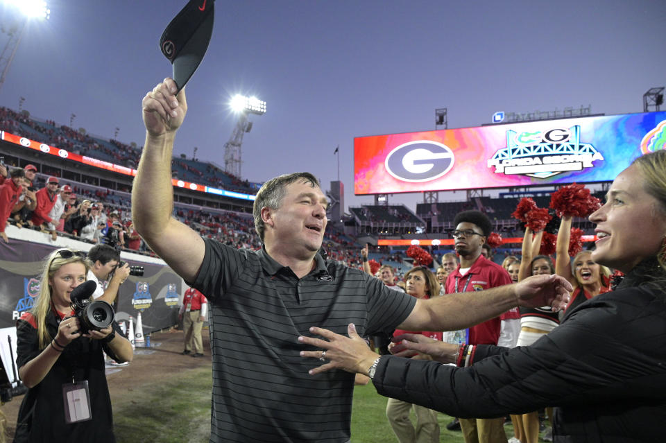 FILE - Georgia head coach Kirby Smart, center, is greeted by his wife Mary Beth Smart, right, after a win over Florida in an NCAA college football game, Saturday, Oct. 30, 2021, in Jacksonville, Fla. Georgia is No. 3 in The Associated Press preseason college football poll, released Monday, Aug. 15, 2022. (AP Photo/Phelan M. Ebenhack, File)