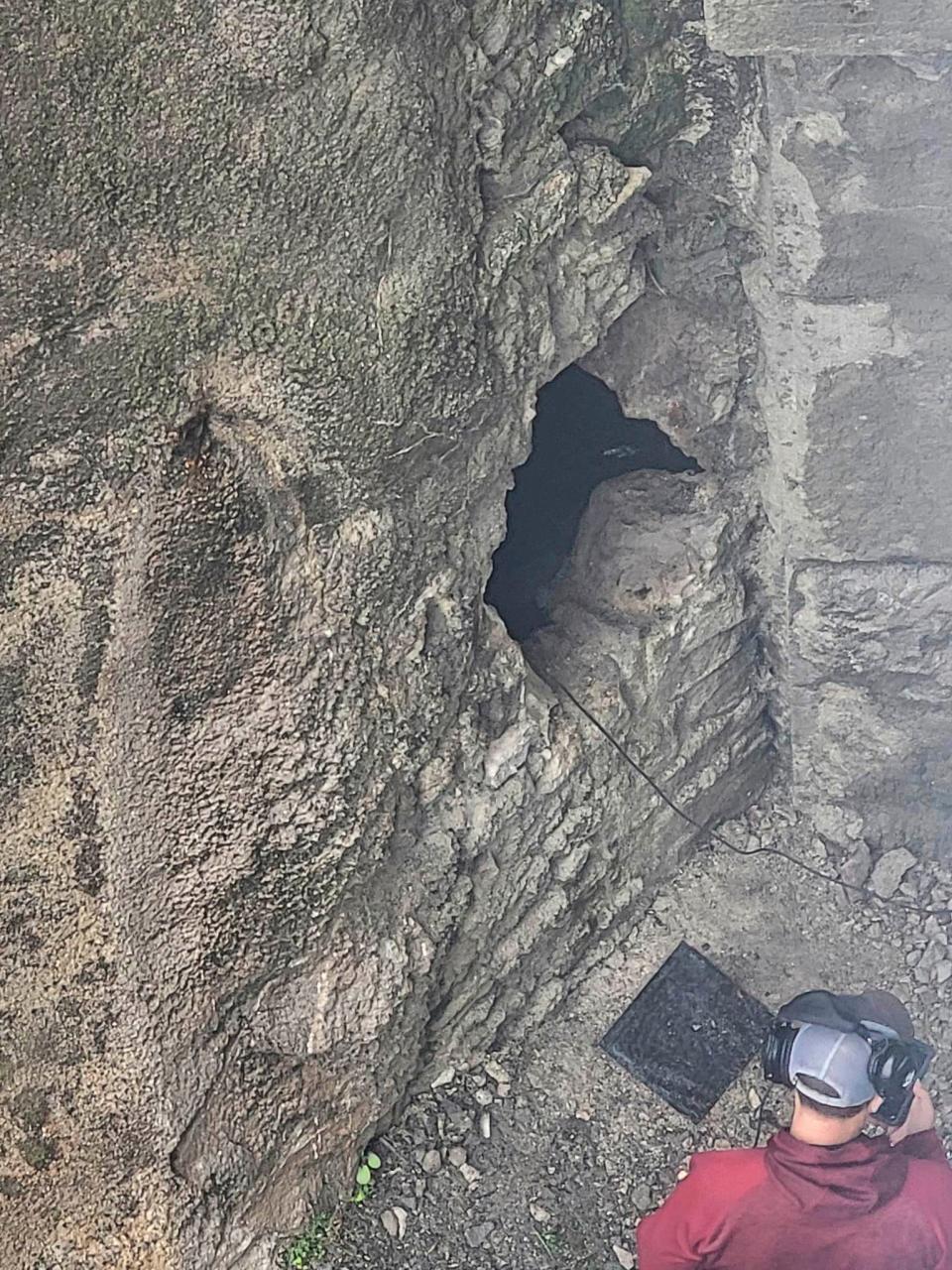 This photo provided by Jeremy Swiatowy shows rescue workers as they breach a wall with a sledgehammer June 12, 2023, before going through the hole to help rescue people stuck inside the caves in Lockport, N.Y.