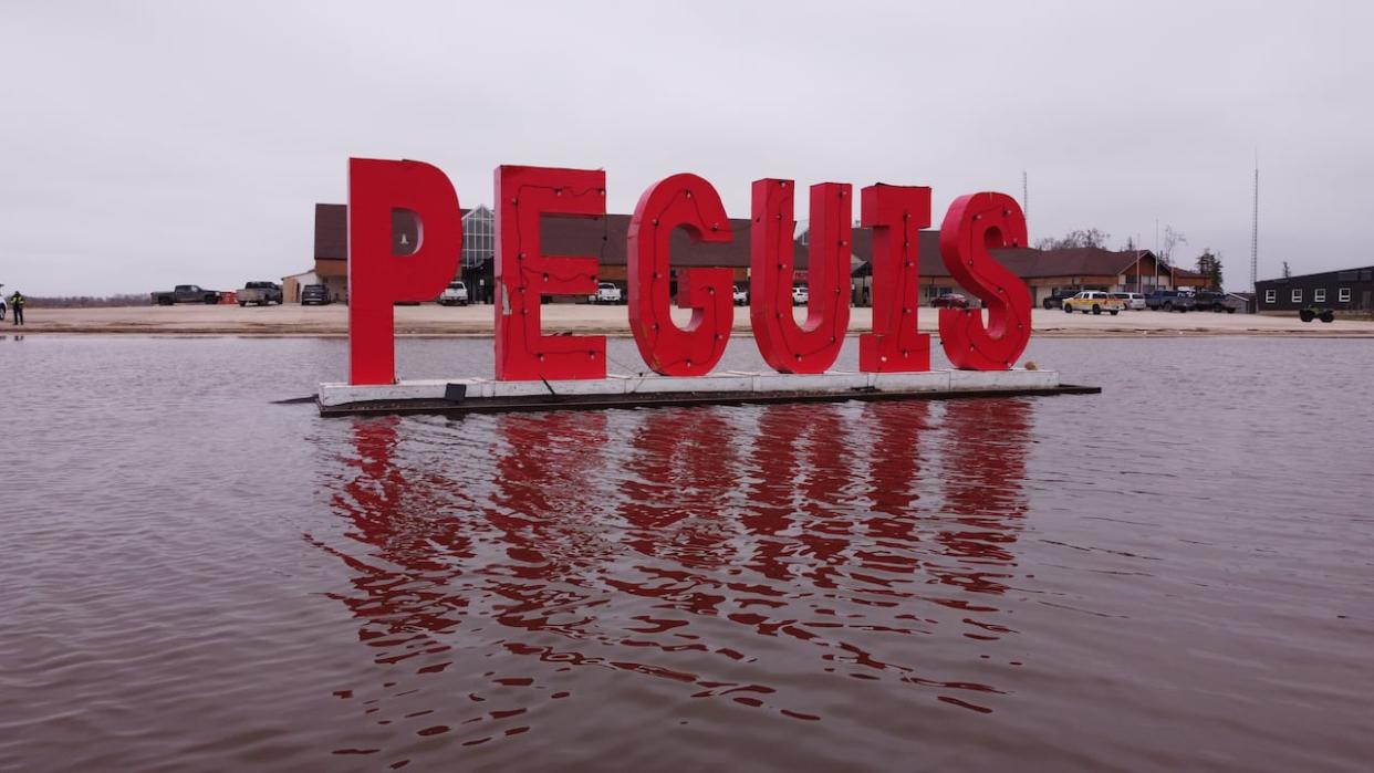 The Peguis First Nation sign is surrounded by flood waters in May 2022. The First Nation, which has been struggling for more than a century to recover from a forced relocation to a flood-prone area of Manitoba's Interlake, has filed a lawsuit seeking $1 billion in flood damages from Ottawa, Manitoba and two municipalities. (Jaison Empson/CBC - image credit)