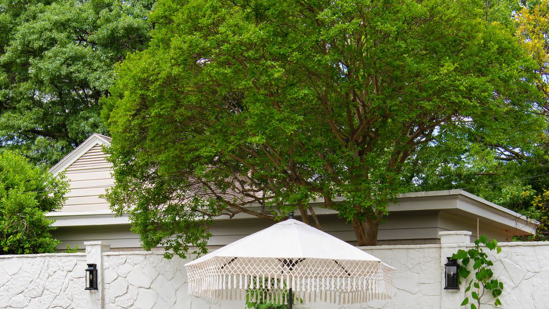 1930s cottage designed by burkle creative pergola patio anchoring the main entertaining space at the home of designer javier burkle, an ever changing mix of furnishings can work for cocktail hours or seated dinners the stone wall is a reference to the haciendas of mexico, burkle's home country paints greek villa, sherwin williams walls onyx black, glidden accents table ralph lauren home chairs cb2 rugs serena lily sofas one kings lane, in pindler sunbrella umbrella world market daybed cb2