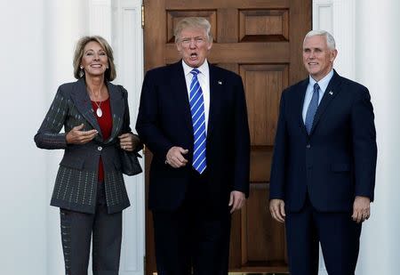 U.S. President-elect Donald Trump (C) and Vice President-elect Mike Pence stand with Betsy DeVos (L) before their meeting at the main clubhouse at Trump National Golf Club in Bedminster, New Jersey, U.S., November 19, 2016. REUTERS/Mike Segar/File Photo