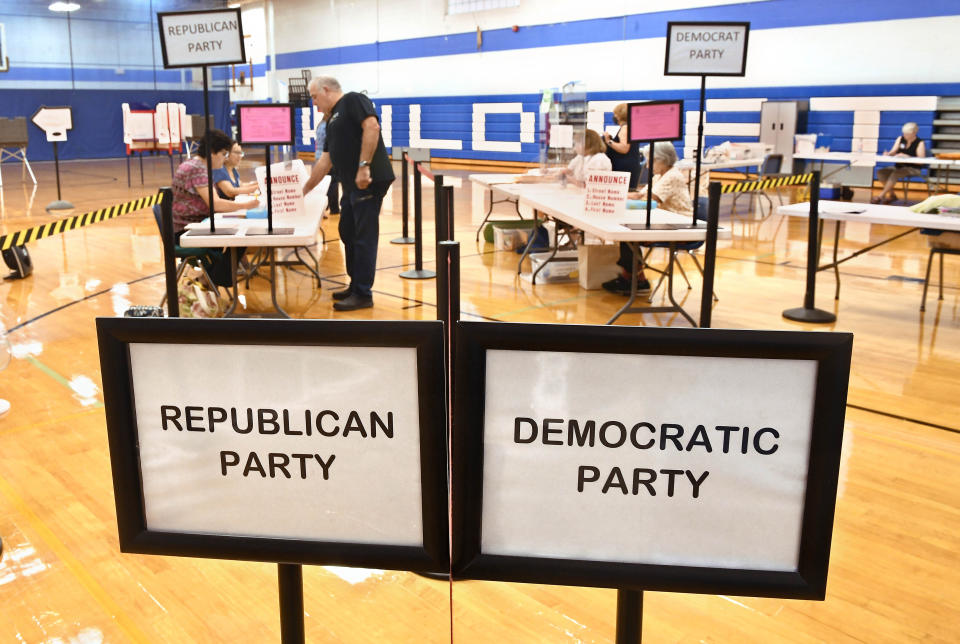 A voter checks in at Suffield Middle School on primary election day, Tuesday, Aug. 9, 2022, in Suffield, Conn. Suffield is one of several small towns in Connecticut where control was flipped from Democrats to Republicans in 2021 municipal races. (AP Photo/Jessica Hill)