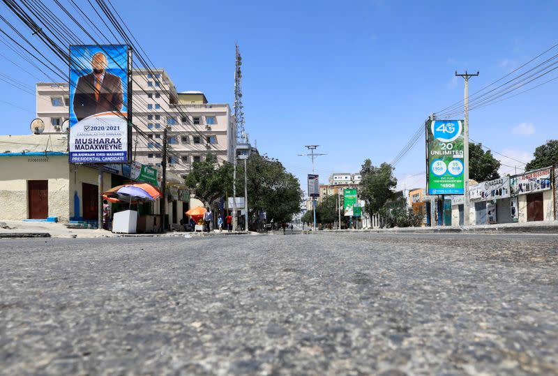 Somali people walk along a deserted street during fighting between Somali government forces and opposition troops over delayed elections in Mogadishu