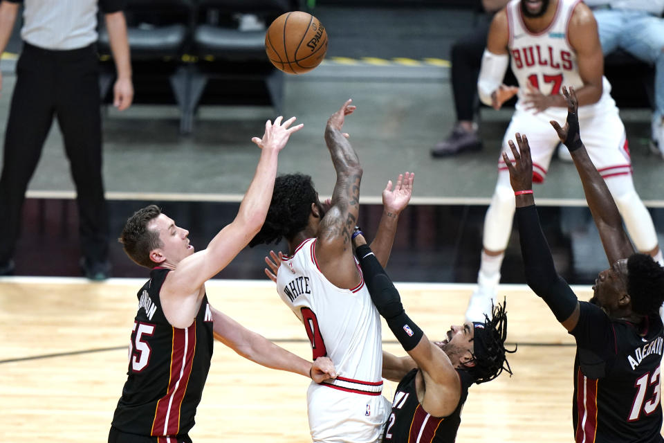 Chicago Bulls guard Coby White (0) commits an offensive foul as Miami Heat guard Duncan Robinson, left and guard Gabe Vincent, right, defend during the second half of an NBA basketball game, Monday, April 26, 2021, in Miami. (AP Photo/Lynne Sladky)