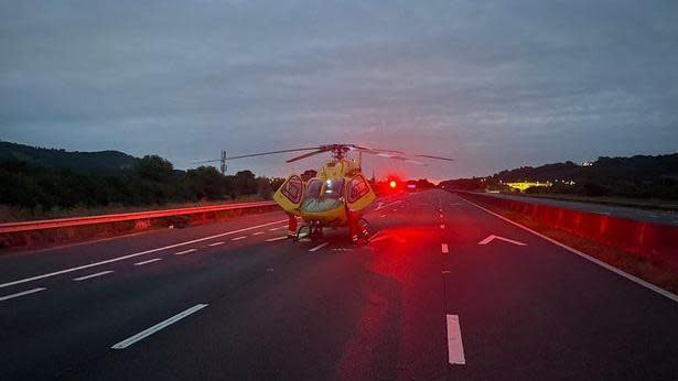 A medical helicopter landed in the middle lane of the M5 motorway. The sky is still dark as dawn hasn't broken yet 