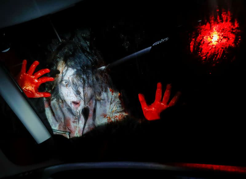 An actor dressed as a zombie performs during a drive-in haunted house show by Kowagarasetai, for people inside a car in order to maintain social distancing amid the spread of the coronavirus disease (COVID-19), in Tokyo