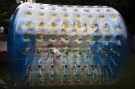 A boy wearing a face mask to protect against the coronavirus plays inside an inflatable tube at a public park in Beijing, Saturday, July 11, 2020. New coronavirus cases have dropped sharply in China, and authorities are turning their attention to concerns that the virus could spread through imported food. (AP Photo/Mark Schiefelbein)