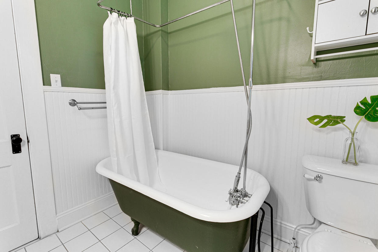 Bathroom with Green Walls and Clawfoot Tub with a shower curtain. (Bryan Chavez / Getty Images)