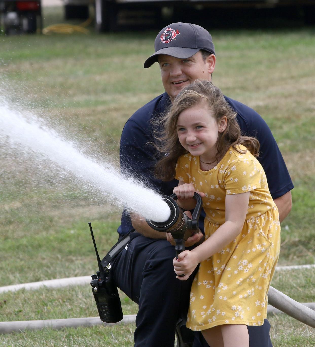 Leia Scarella, 6, sprays water with help from her dad, Alliance Fire Department firefighter Jesse Scarella, during the Carnation Festival Pump-In & Muster on Sunday, Aug. 7, 2022, at Glamorgan Castle.