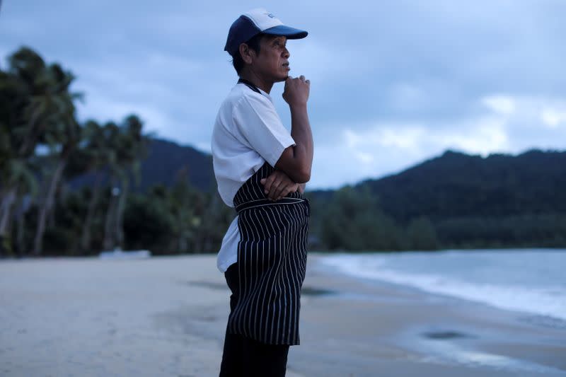 FILE PHOTO: A chef stands on an empty beach as he waits for the costumers at Koh Chang island in Thailand