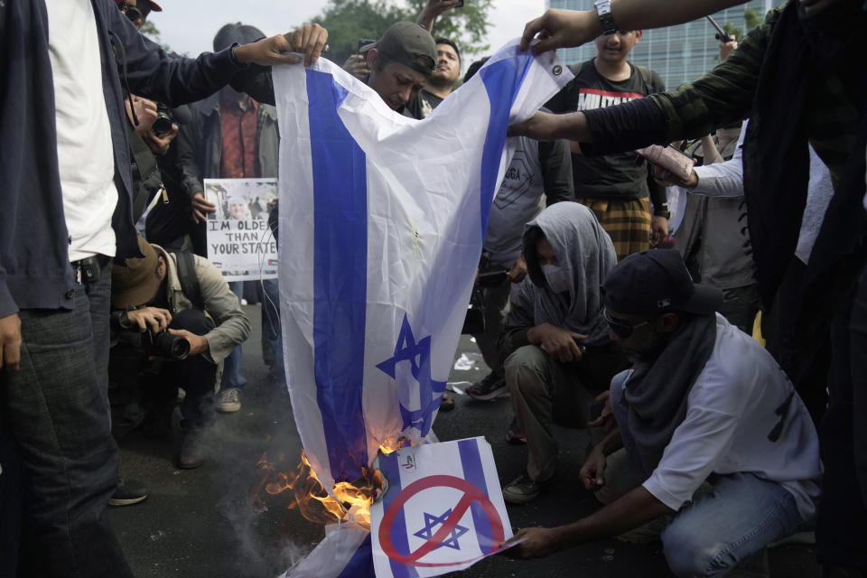 Protesters burn an Israeli flag and a poster of Israeli Prime Minister Benjamin Netanyahu during a rally supporting the Palestinian people outside the U.S. Embassy in Jakarta, Indonesia, Friday, Oct. 20, 2023. Hundreds of people staged protests in Indonesia's capital Friday to denounce the staunch American support for Israel and demand an end to Israeli airstrikes on the Gaza Strip. (AP Photo/Dita Alangkara)