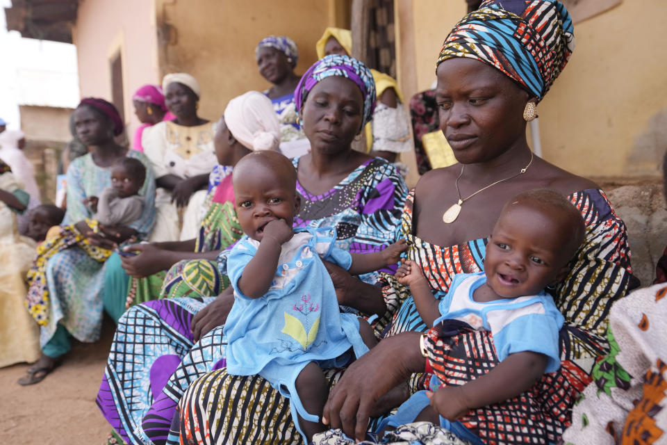 Dorcas Simon, 38-year-old, plays with her twin daughters during a food training event in Kaltungo's Poshereng Nigeria, Sunday, June 2, 2024. Dorcas Simon's nine-month-old twin daughters cried nonstop and tugged at her clothes for attention but also for food. They've barely had any food in the past 24 hours. But that's not new. It's all too obvious in their protuberant abdomens and heads too big for their tiny bodies. She knows they need food but finding what to eat is a struggle in this part of northern Nigeria where conflict and climate change have limited earnings of families and their access to farmlands. Even Simon's breastmilk is barely enough for her children. (AP Photo/Sunday Alamba)