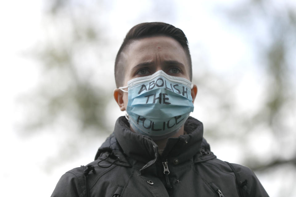 A person wearing a face mask reading "Abolish the Police" attends a vigil honoring the life of police shooting victim 13-year-old Adam Toledo, Sunday, April 18, 2021, in Chicago's Douglass Park. (AP Photo/Shafkat Anowar)