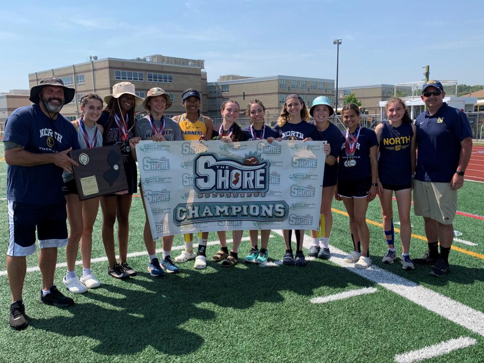 Toms River North girls track poses with the Shore Conference title banner and trophy
