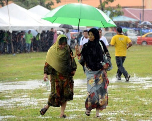 Two Muslim women make their way across a flooded field to listen to opposition leader Anwar Ibrahim speak at a election rally in Ulu Melaka, May 3, 2013. Anwar said only fraud can stop his Malaysian opposition from scoring a historic election win as the rival sides launched a last-ditch campaign blitz Saturday on the eve of a tense vote