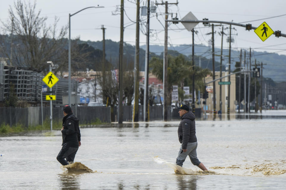 People walk through floodwaters in Watsonville, Calif., Saturday, March 11, 2023. Gov. Gavin Newsom has declared emergencies in 34 counties in recent weeks, and the Biden administration approved a presidential disaster declaration for some on Friday morning, a move that will bring more federal assistance. (AP Photo/Nic Coury)