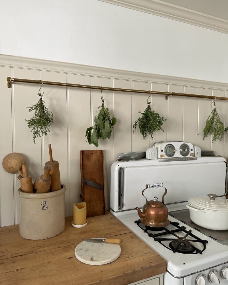 Herbs drying on brass rail in renovated kitchen.