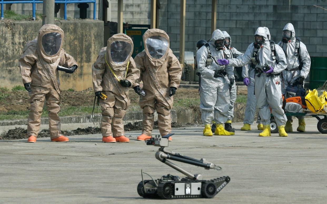 Soldiers of the U.S. Army 23rd chemical battalion, wearing anti-chemical suits, watch a bomb disposal robot during a demonstration of their equipment in Uijeongbu, north of Seoul - AP