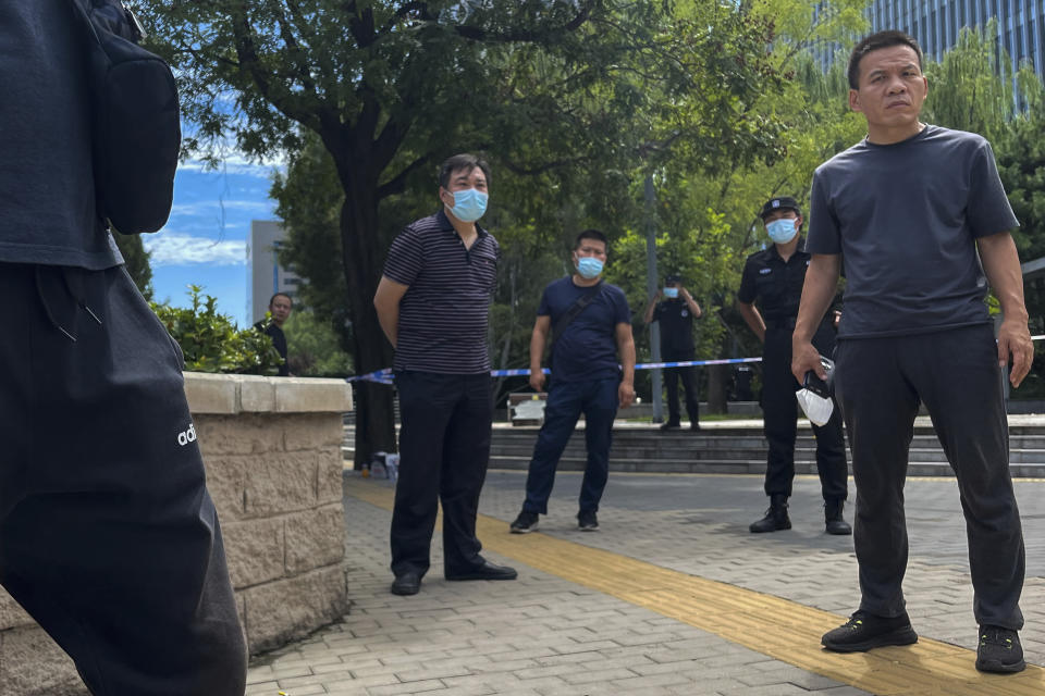 Plain clothes policemen wearing face masks stand watch as they stop journalists from getting near to the No. 1 Intermediate People's Court, where Zhou Xiaoxuan, a former intern at state broadcaster China Central Television, filling her appeal case against CCTV host Zhu Jun of groping and forcibly kissing her in 2014, in Beijing, Wednesday, Aug. 10, 2022. A Chinese court rejected an appeal Wednesday from a woman seeking an apology and damages in a high-profile case from the country's short-lived #MeToo movement. (AP Photo/Andy Wong)