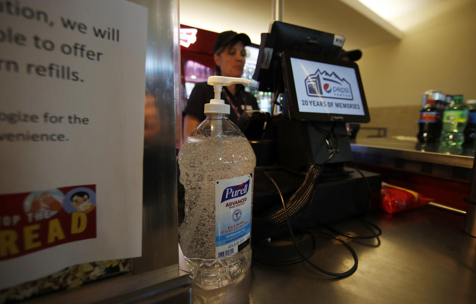 A large bottle of hand sanitizer stands next to the cash register at a food stand in Pepsi Center before the Colorado Avalanche host the New York Rangers in the first period of an NHL hockey game Wednesday, March 11, 2020, in Denver. (AP Photo/David Zalubowski)