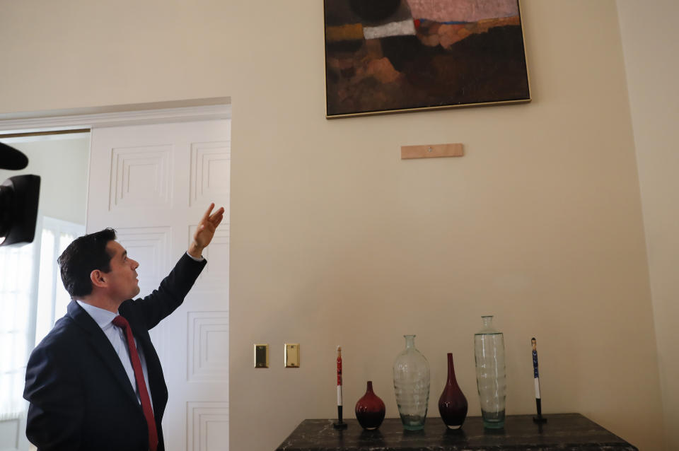 In this Sept. 17, 2019, photo, Carlos Vecchio, an exiled politician who the U.S. recognizes as Venezuela’s ambassador, points to a section of a wall where artwork once hung inside the Ambassador's residence in Washington. U.S. officials are investigating the possible looting from Venezuela of valuable European and Latin American artwork they believe is being quietly plundered by government insiders as Nicolas Maduro struggles to keep his grip on power. “This is just the tip of the iceberg,” Vecchio said. “If this is what they’ve managed to do with some artwork at a single diplomatic mission, you can imagine what they’ve done inside Venezuela.” (AP Photo/Pablo Martinez Monsivais)