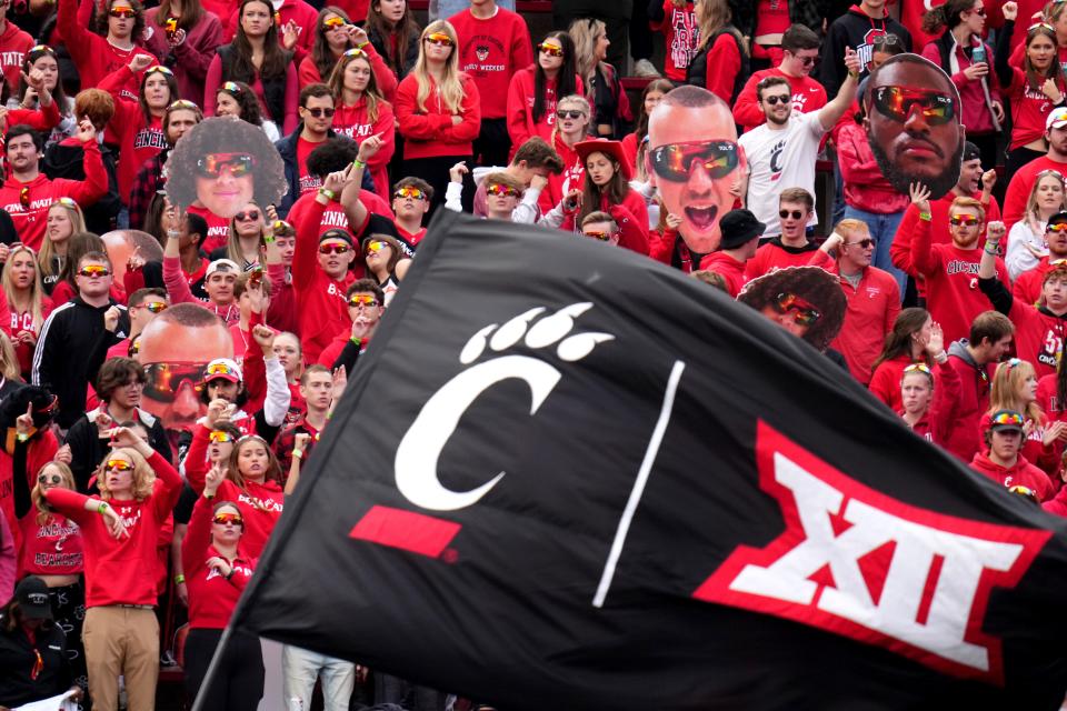 The Cincinnati Bearcats student section cheers on the team as a flag with the C-paw and Big 12 Conference logos is waved after a touchdown in the second quarter during a college football game between the Baylor Bears and the Cincinnati Bearcats, Saturday, Oct. 21, 2023, at Nippert Stadium in Cincinnati.