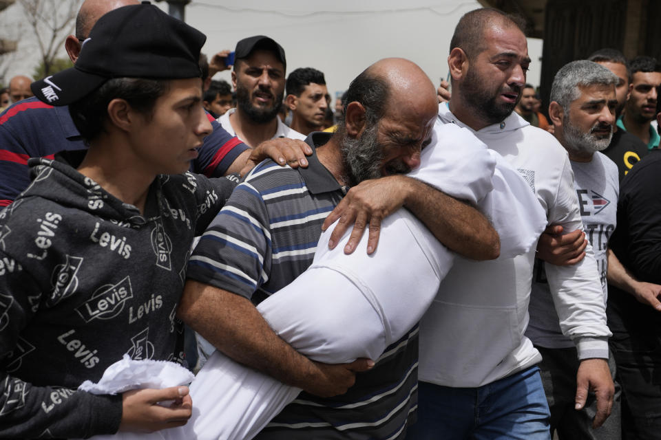 A man cries as he carries the body of a young girl during the funeral procession for seven people killed when a boat packed with migrants sunk over the weekend as the Lebanese navy tried to force it back to shore, in Tripoli, north Lebanon, Monday, April 25, 2022. The small vessel was carrying nearly 60 people, many times its capacity, when the disaster struck on Saturday night. The tragedy was the latest in a growing trend involving mostly Lebanese and Syrians trying to travel to Europe from Lebanon in search of better lives. (AP Photo/Hassan Ammar)