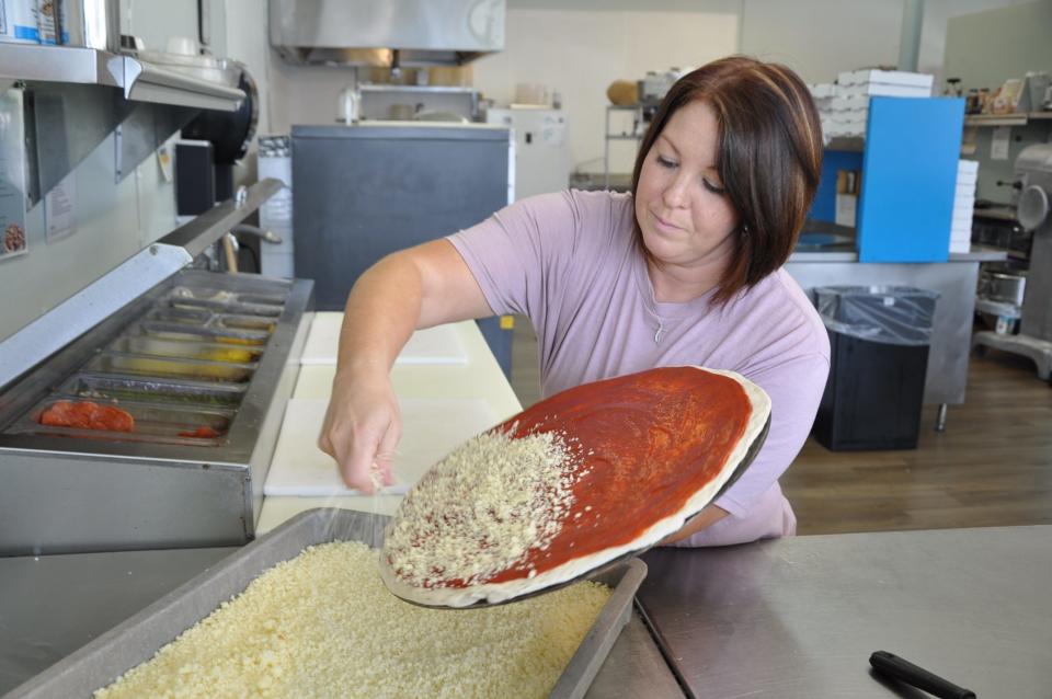 Tara Dudley, co-owner of Dudley's G's Pizza World, puts cheese on a large pizza. The Dudleys said all the pizzas are made fresh with fresh ingredients.