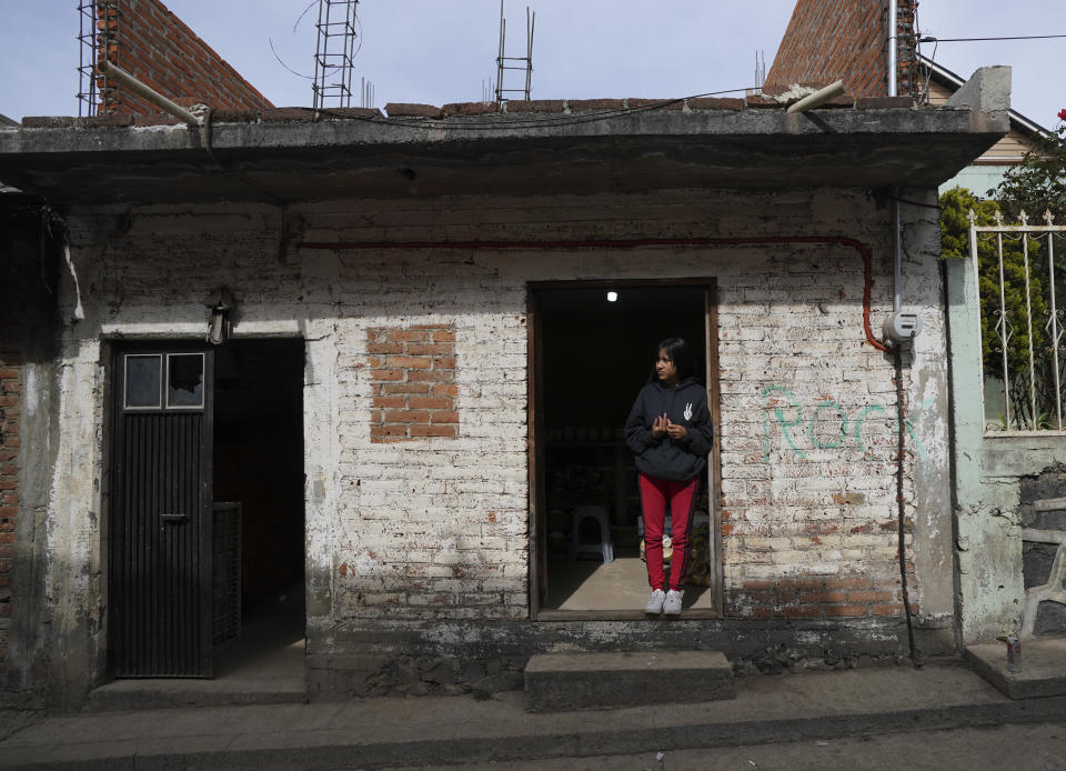 Andrea Sanchez, who migrated without documents to California with her family as a young child in 2002 and studied at U.S. schools through the sixth grade, stands in the doorway of her home in the Purepecha Indigenous community of Comachuen, Michoacan state, Mexico, Wednesday, Jan. 19, 2022. When her family returned to Comachuen, she said, “it was a big shock ... it was really different.” In the decade since, she has learned to love her hometown, even if it doesn’t have the large homes and well-kept yards she saw in her childhood. “This is home. This culture calls to me.” (AP Photo/Fernando Llano)