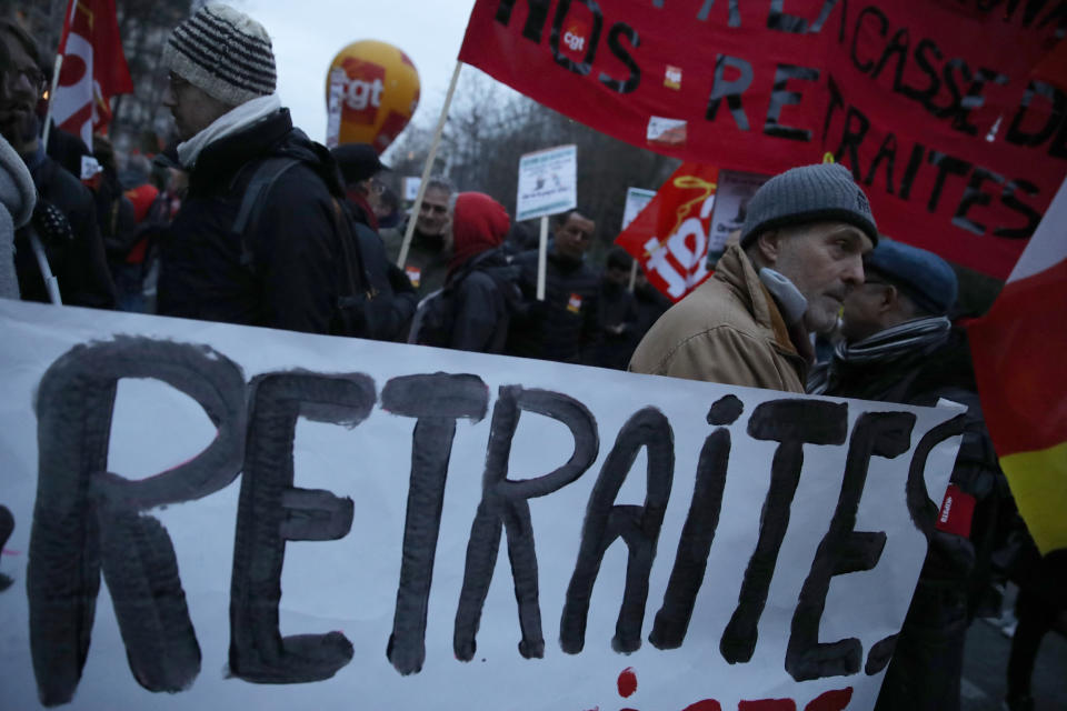 Protesters march with a banner reading "Pensions" during a demonstration Tuesday, Dec. 10, 2019 in Paris. French airport employees, teachers and other workers joined nationwide strikes Tuesday as unions cranked up pressure on the government to scrap upcoming changes to the country's national retirement system. (AP Photo/Thibault Camus)