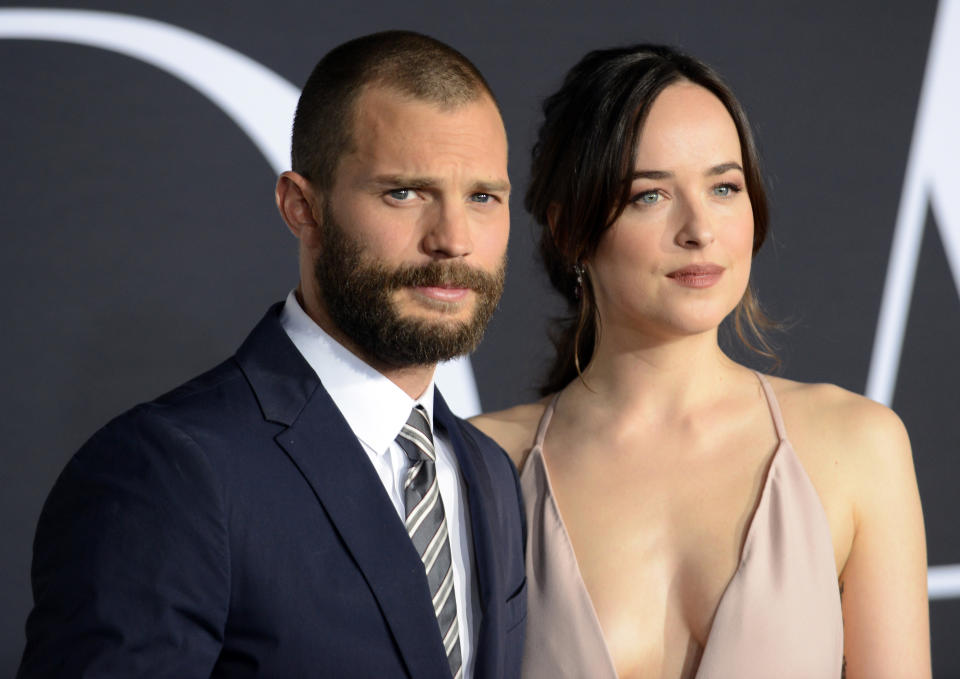 Jamie Dornan in a suit and Dakota Johnson in a sleeveless gown pose together at a formal event