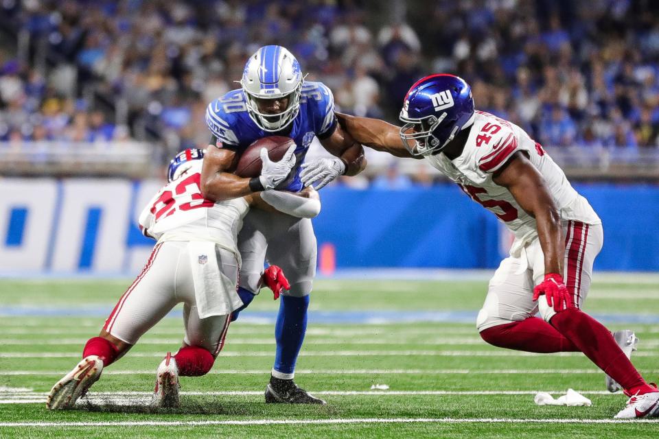 Detroit Lions running back Devine Ozigbo (30) runs against New York Giants linebacker Habakkuk Baldonado (45) and New York Giants safety Alex Cook (23) during the second half of a preseason game at Ford Field in Detroit on Friday, Aug. 11, 2023.