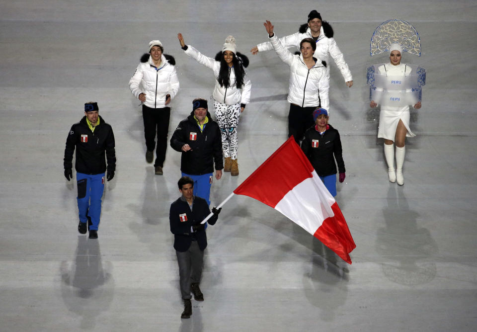 Roberto Carcelen of Peru holds his national flag and enters the arena with teammates during the opening ceremony of the 2014 Winter Olympics in Sochi, Russia, Friday, Feb. 7, 2014. (AP Photo/Charlie Riedel)