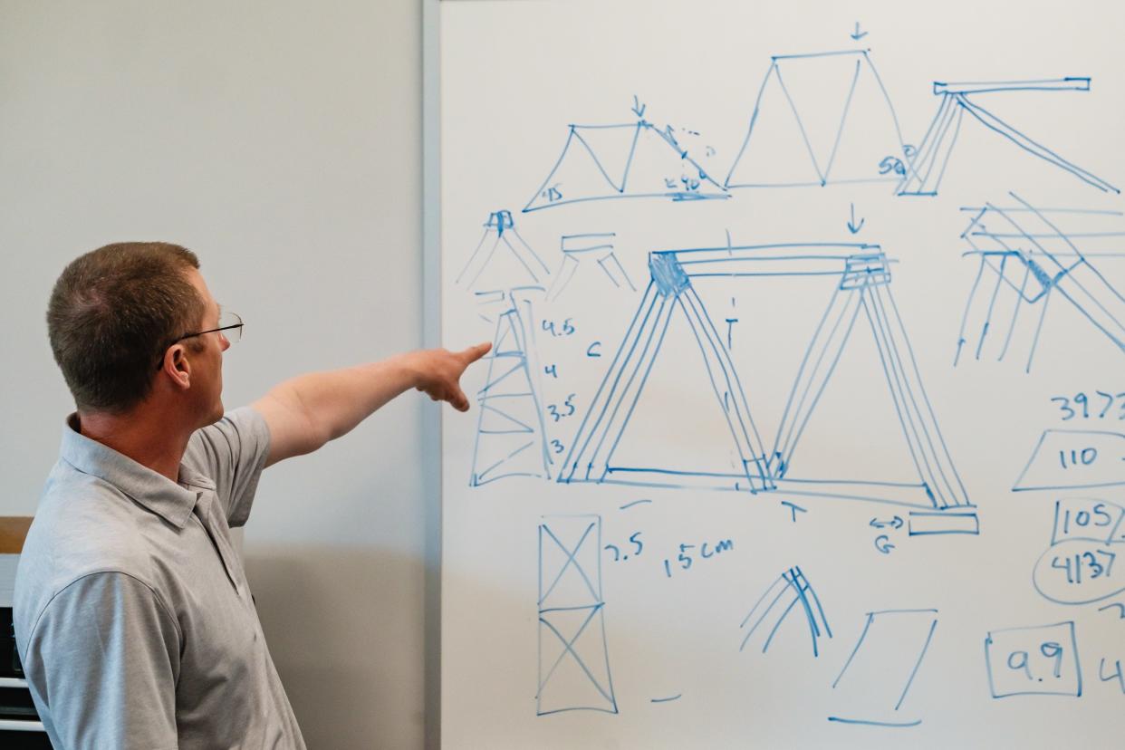 Carl Conrad, adviser to two Dover High School students competing in this year's annual International Bridge Building Competition, talks about scribblings on a white board related to engineering, at Dover High School.