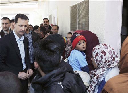 Syria's President Bashar al-Assad speaks with children during his visit to displaced Syrians in the town of Adra in the Damascus countryside March 12, 2014, in this handout photograph released by Syria's national news agency SANA. REUTERS/SANA/Handout via Reuters