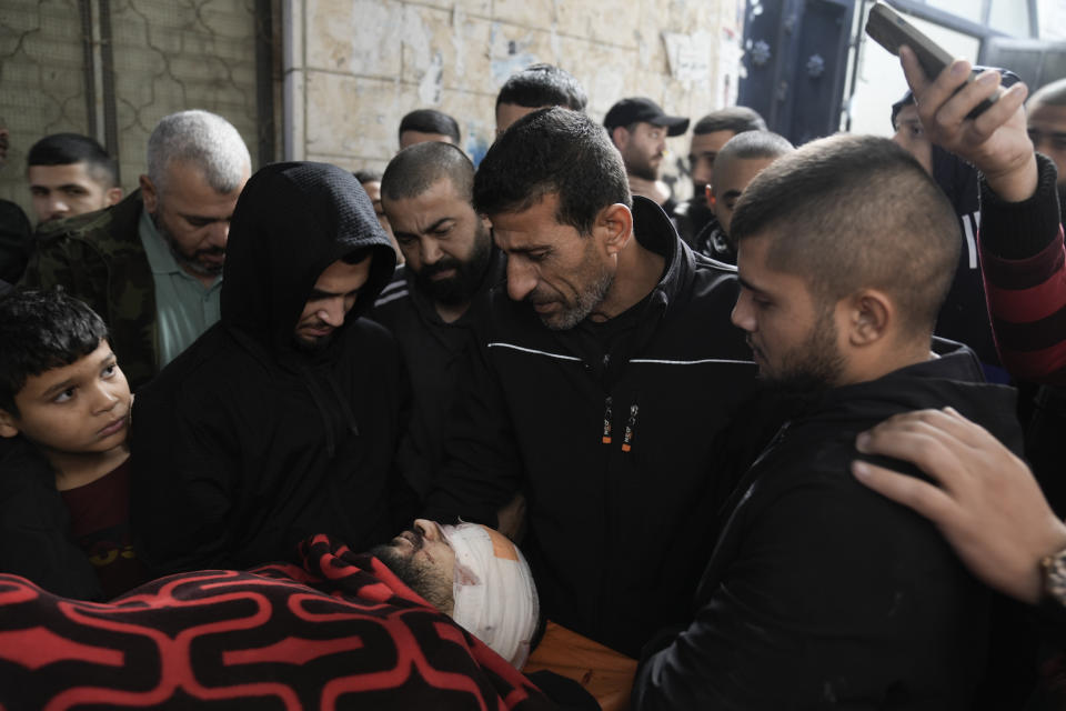 Un grupo de palestinos rodea el cadáver de un hombre que murió durante una redada del ejército israelí en el campamento de refugiados Nur Shams, en Cisjordania, el domingo 17 de diciembre de 2023. (AP Foto/Majdi Mohammed)