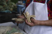 Felipa de Jesus Otzoy, 55, counts her hand-made corn tortillas at her market stall in Guatemala City, Saturday, Oct. 16, 2021. For millions of Guatemalan families hand-made corn tortillas are indispensable with every meal, but many of those tortillas pass through the hands of girls and young women trapped in poverty. (AP Photo/Moises Castillo)