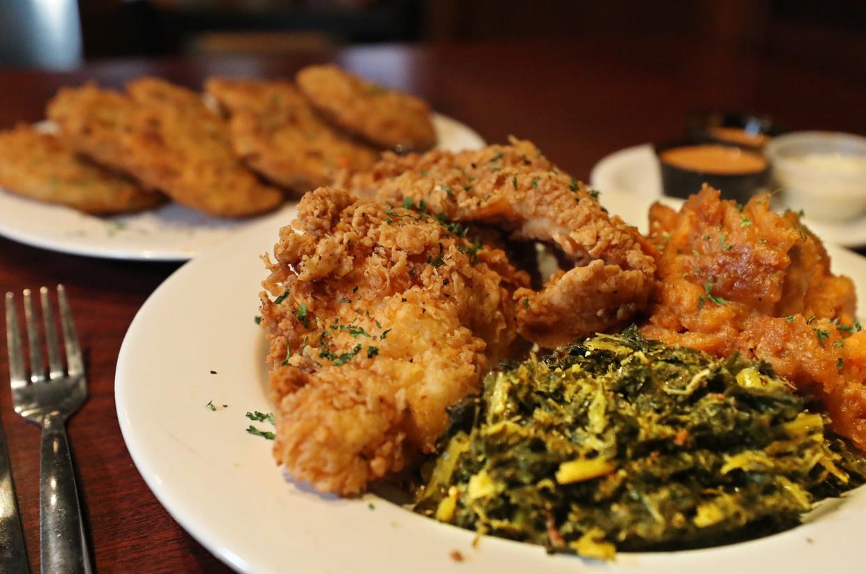 The fried catfish platter is pictured with collard greens and candied yams and a plate of fried green tomatoes as an appetizer at Sweetbeats Sports & Soul Food Karaoke Bar in Akron.
