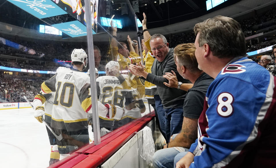 As members of the Vegas Golden Knights, left, celebrate a a goal by center Jonathan Marchessault that knotted the score against the Colorado Avalanche, Golden Knights fans cheer in third period of Game 5 of an NHL hockey Stanley Cup second-round playoff series Tuesday, June 8, 2021, in Denver. The Golden Knights won 3-2 in overtime. (AP Photo/David Zalubowski)